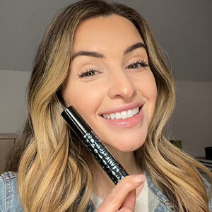 light skinned model holding mascarab tube up while smiling