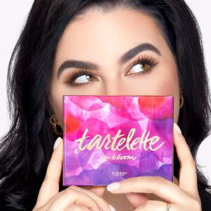 light skinned model holding eyeshadow palette in front of her face