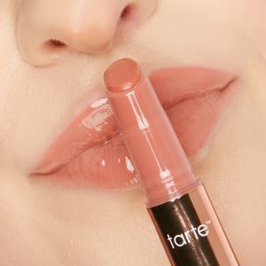 light skinned model holding an open maracuja juicy lip plump tube over her closed, glossed lips